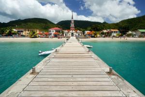 a pier in the water with a church on a beach at La Belle Escapade in Quartier du Fond Fleuri