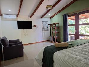 a bedroom with a bed and a chair and a television at Olla é Mono Ecolodge in Sarapiquí +11 photos