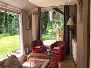 a living room with two red chairs and a window at Cottage near the Mill Pond with a beautiful garden in Le Ponchel