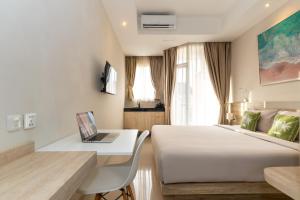 a bedroom with a bed and a desk with a laptop at Bali Bustle Pararaton Coliving and Coworking Space in Legian