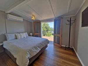 a bedroom with a bed and a large window at Tweed River Waterfront Cottage in Murwillumbah +15 photos
