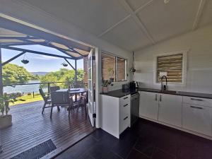 a kitchen and dining room with a table and a balcony at Tweed River Waterfront Cottage in Murwillumbah
