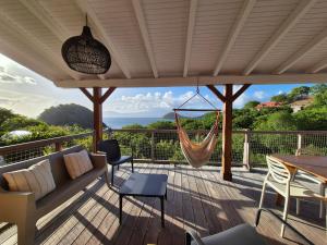 a porch with a hammock and a table and chairs at Villa Bois coco Les Saintes in Terre-de-Haut