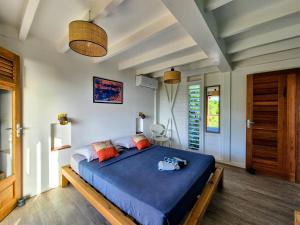 a bedroom with a bed with blue sheets and orange pillows at Villa Bois coco Les Saintes in Terre-de-Haut