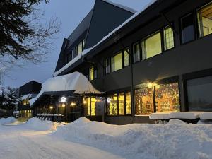 a building covered in snow in front of a street at Ski-in, Ski-out Iwatake Apartments in Hakuba