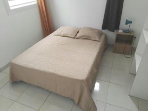 a bed in a room with a white tiled floor at T3 climatisé avec terrasse proche plages in Rivière-Pilote