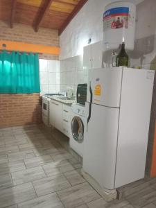 a kitchen with a white refrigerator and a washing machine at Casa Camila in Villa Cura Brochero