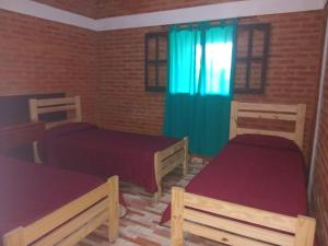 a bedroom with two beds and a blue curtain at Casa Camila in Villa Cura Brochero