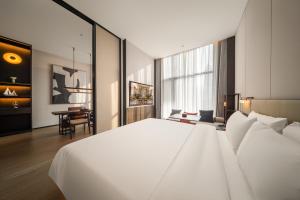 a bedroom with a large white bed and a desk at Madison Hotel Jinan CBD in Jinan