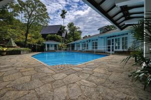 a swimming pool in front of a house at Forest Edge Resort in Kitulgala
