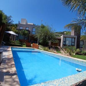 a large blue swimming pool in front of a house at Terralagum in Villa Parque Siquiman