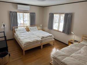 a bedroom with two beds and two windows at 2 Peaks Snow Lodge in Hakuba