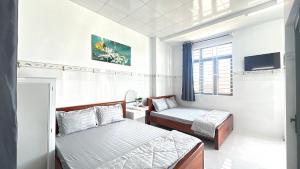 a small room with two beds and a tv at Nhà Nghỉ Như Ý in Phan Rang–Tháp Chàm