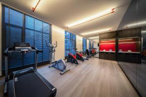a gym with several treadmills and exercise equipment and windows at Madison Hotel Jinan CBD in Jinan