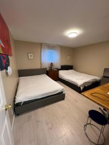 a room with two beds and a table and a desk at Brentwood Home in Burnaby