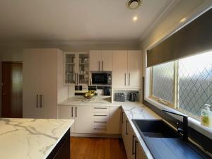 a kitchen with white cabinets and a large window at House on Heron in Mildura