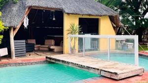 a house with a swimming pool with a thatch roof at De whytehouse Mogalatsane in Marble Hall