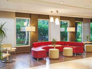 a lobby with a red couch and tables and windows at Ibis Cornella in Cornellà de Llobregat