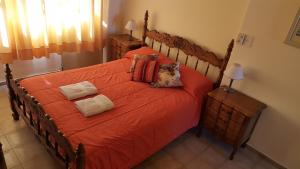 1 dormitorio con 1 cama grande de color naranja y 2 almohadas en Virginia Departamentos en San Rafael