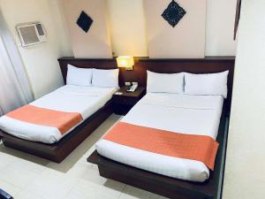 a hotel room with two beds and a night stand at Roxas Midtown Hotel in Roxas City