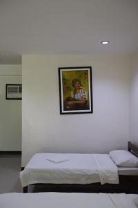 a white room with a bed with a picture on the wall at Meg's Resort in Andoon +26 photos