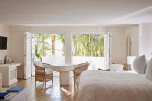 a white bedroom with a bed and a table and chairs at Raes on Wategos in Byron Bay