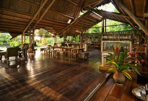 a restaurant with wooden floors and tables and chairs at Maravilla Ojo Del Mar Naturelodge in Puerto Jiménez