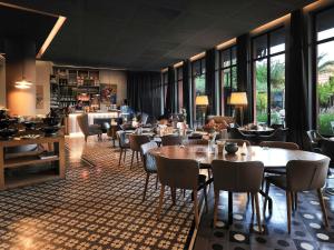 a restaurant with tables and chairs and windows at Novotel Marrakech Hivernage in Marrakesh