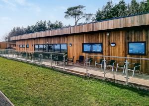 a large wooden building with chairs and tables on it at Woodlands Park Lodges At Haystax in Knitsley