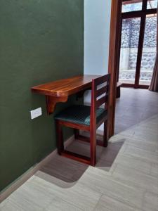 a wooden table and a chair next to a green wall at Villa Monarca - Markinkia Estancia Amazónica in Macas
