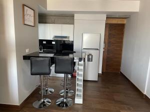 a kitchen with a bar with stools and a refrigerator at Departamento en Torre Historicah in Monterrey