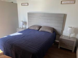 a bedroom with a bed with a blue comforter and two lamps at Departamento en Torre Historicah in Monterrey +35 photos
