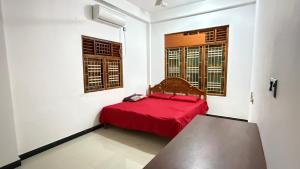 a bedroom with a red bed and two windows at Nikshi Guest House in Nikawatawana