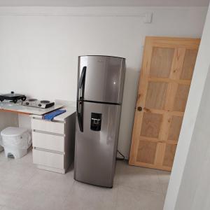 a stainless steel refrigerator in a kitchen with a door at Apartamentos Las Orquideas in San Pedro