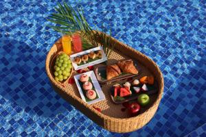 a basket of food on a table in a pool at GAIA Hotel & Residence Phu Quoc in Phú Quốc