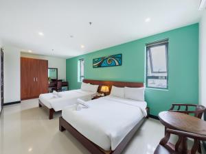 a bedroom with two beds and a blue wall at Quoc Cuong Center Da Nang Hotel by Haviland in Danang