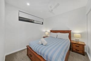 a bedroom with a bed with a blue and white striped sheets at The Corso - Central Maroochydore Apartment in Maroochydore +15 photos