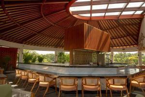 a restaurant with a bar with chairs under a roof at Adiwana Alas Harum in Ubud