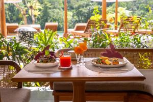 a wooden table with two plates of food and drinks at Adiwana Alas Harum in Ubud