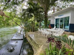 a house with a table and chairs next to a river at Baan LungYod Resort in Phetchaburi