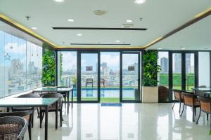 a restaurant with tables and chairs and windows at Quoc Cuong Center Da Nang Hotel by Haviland in Danang