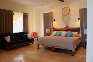 a bedroom with a bed and a chair and a couch at Club de Playa Sóol in Telchac Puerto +32 photos