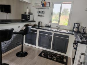 a kitchen with a sink and a counter with a stool at Case Créole Soalaze in Salazie