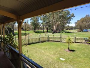 a porch with a fence and a yard with a palm tree at Riverside Golf Club in Gol Gol