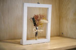 a vase with flowers in a white frame on a table at Fierement inn in Sapporo