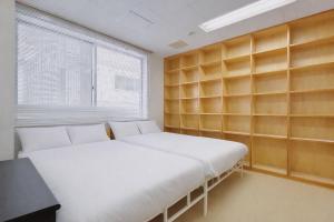 two beds in a room with wooden shelves at Fierement inn in Sapporo