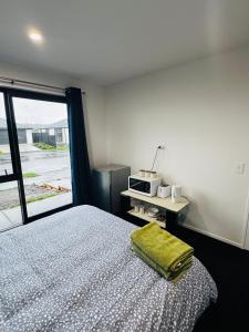 a bedroom with a bed with a microwave and a window at Room with en-suite bathroom in Kaiapoi +13 photos
