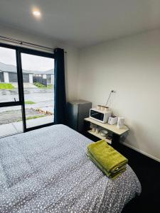 a bedroom with a bed with a microwave and a window at Room with en-suite bathroom in Kaiapoi