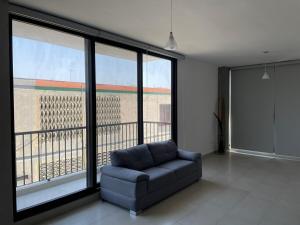a living room with a couch and large windows at Loftstay MYO in Monterrey