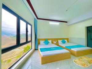 two beds in a room with large windows at Nhà Nghỉ Mũi Giày in Mù Cang Chải